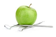 Green apple and dental tools isolated on white