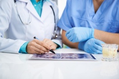 Portrait of female dentist and male surgeon examining teeth x-ray of a patient sitting at the desk in lab.